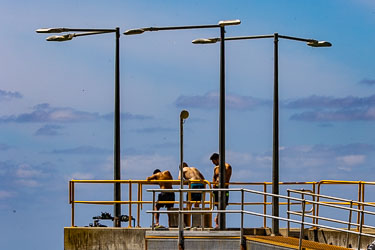 Three youths enjoying themselves on the Flying Fish Cove general cargo jetty. [9859]