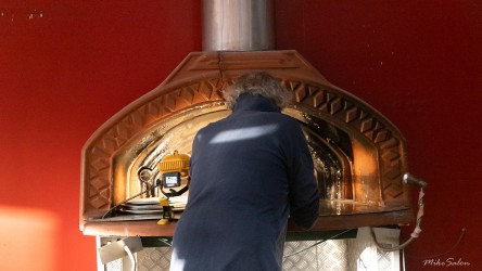 Attending to the oven in Menindee`s pizza shop. The town's most industrious heat source — a rare sight of flame and purpose amid the afternoon stillness. [2275]