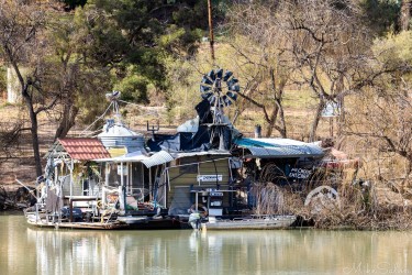 Eccentric residence on the Murray near Paringa, with a sign saying `My Chooks Eat Carp`. Its river ingenuity at its quirkiest — a floating shed powered by a windmill, part workshop, part curiosity.[4663]