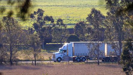 Both trucks and trains passing the driveway entrance to Strathearn Park Lodge. [5508]