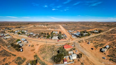 A bird’s‑eye view of the outback town that refuses to fade — red earth, scattered roofs, and endless horizon. That`s the drone pilot, bottom right. [0963]