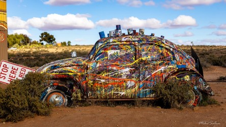 A Volkswagen reborn as art — splashed with colour and half‑claimed by the desert itself. [3013]