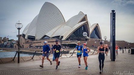 Runners in the Bondi‑to‑Manly Ultra trace the harbour foreshore past the Sydney Opera House, one of the world’s most recognisable landmarks. The 80 km course links Sydney’s eastern and northern beaches, showcasing the city’s unique blend of architecture and natural beauty. [0148]