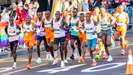 The lead group of elite runners powering through the early kilometres of the 2025 Sydney Marathon, flanked by pace runners and cheered on by spectators. [5215]