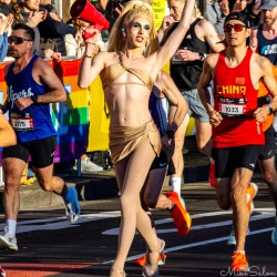 A drag performer in gold costume and heels cheers runners at Taylor Square during the 2025 Sydney Marathon, megaphone in hand and full of pride. The mix of glamour and athletic grit captures the city’s inclusive spirit. [5265]