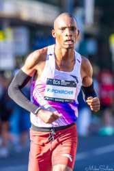 Kenyan runner Victor Kipchirchir powers through Taylor Square during the 2025 Sydney Marathon. His determined expression and strong stride reflect the intensity of elite competition, finishing 11th out of more than 21,000 participants. [5366]